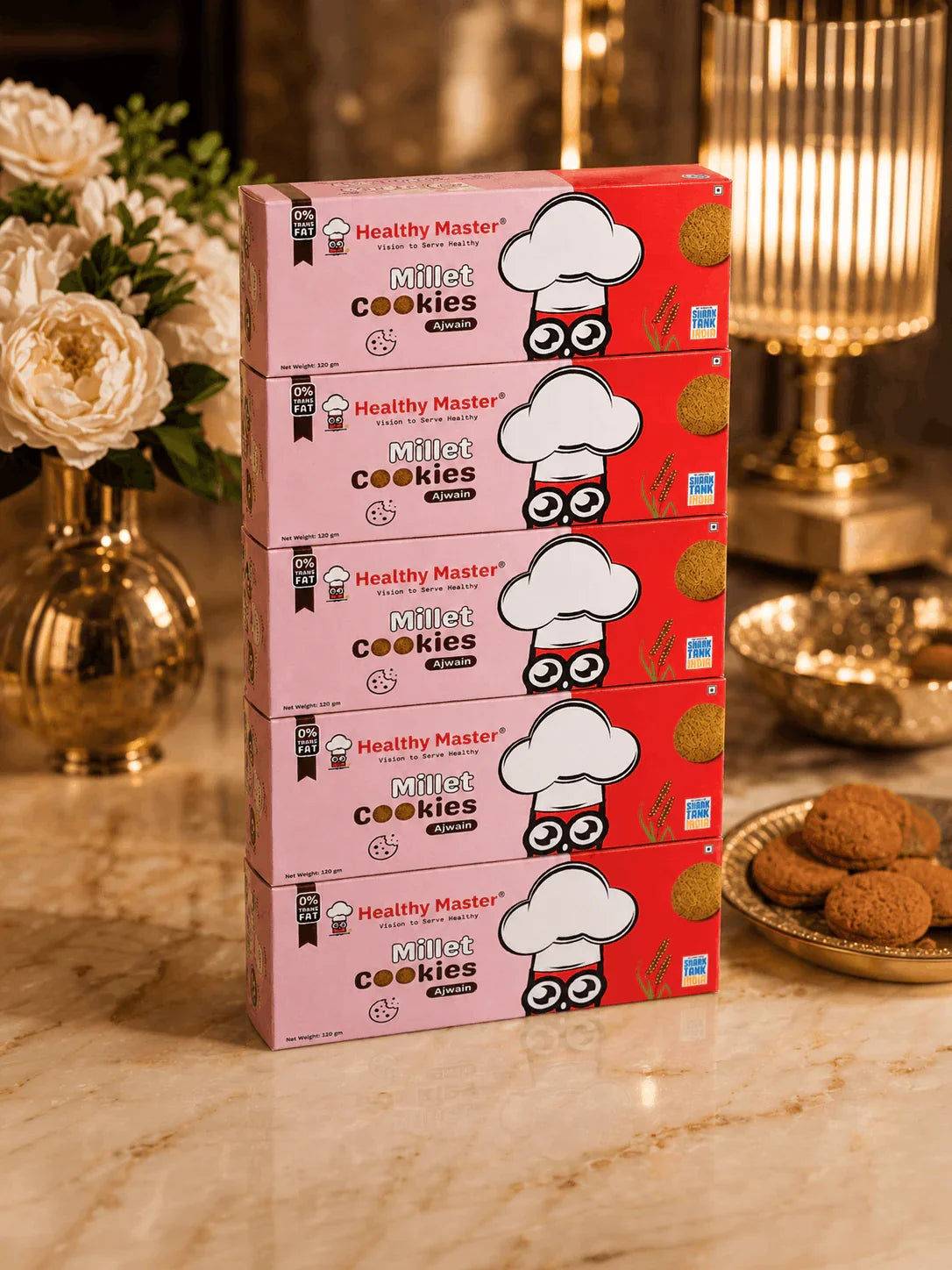 Healthy Master Millet Cookies with Ajwain, 0% trans fat, stacked on marble with golden decor and fresh cookies nearby