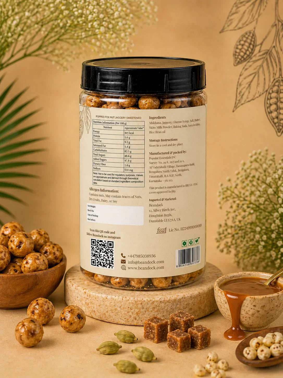 Jaggery-sweetened popped fox nuts in clear jar with nutrition label, surrounded by cardamom, jaggery cubes, and raw nuts