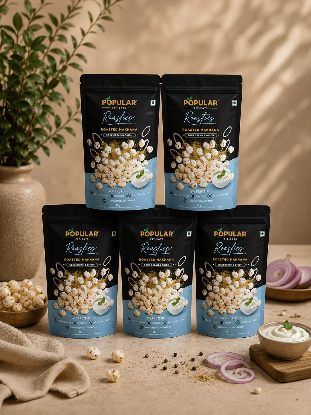 Roasted makhana snack bags with sour cream & onion flavor, high protein, no artificial flavors, displayed with onions and herbs