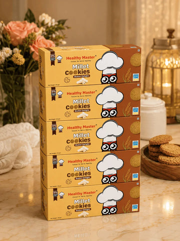Healthy Master Millet Cookies Butter Delight boxes stacked on marble countertop with flowers and cookies nearby